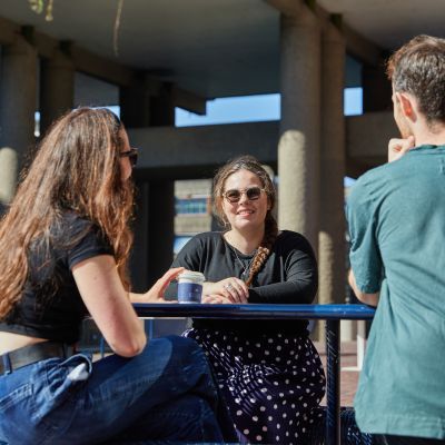 Students sat at a bench table on lakeside terrace on a sunny day